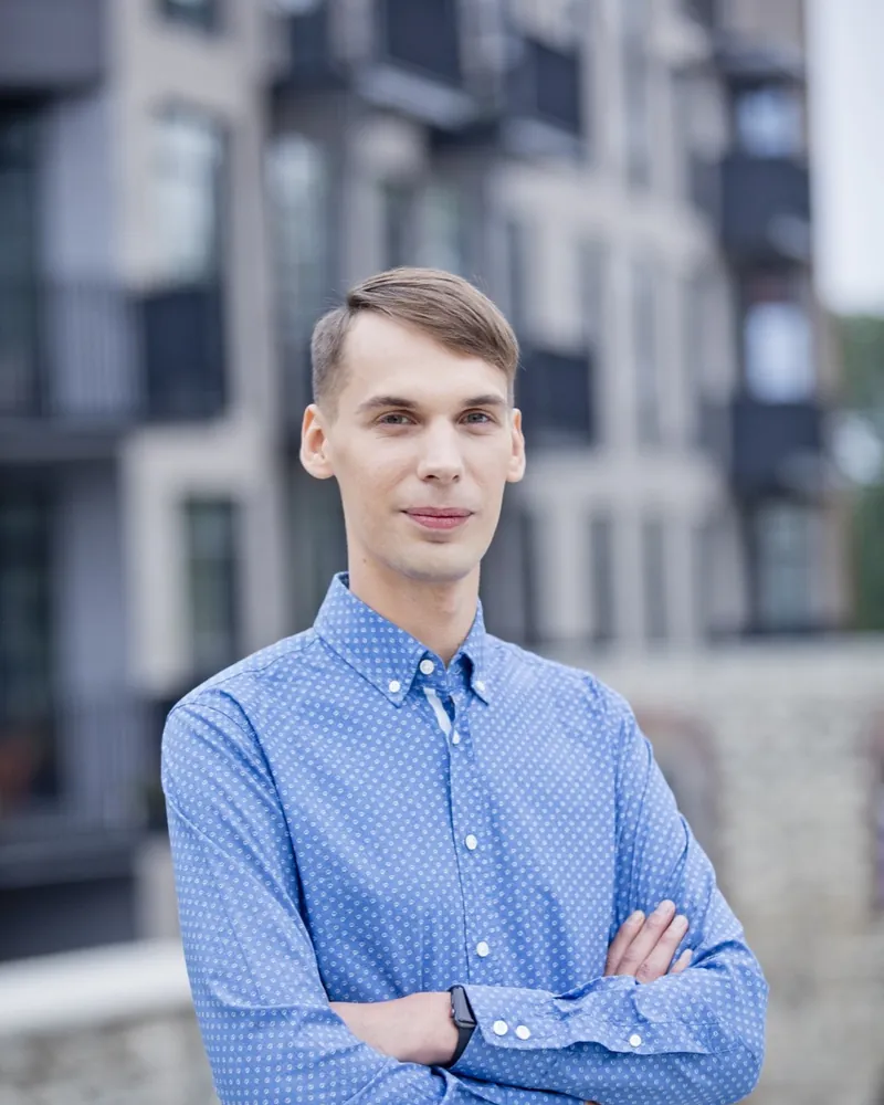 Klemens Arro într-o cămașă albastră, cu brațele încrucișate, zâmbind